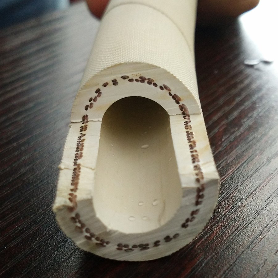 A cut end of food grade hose in white rubber, laid on a bench to show its bore and plies. A cut end of food grade hose in white rubber, laid on a bench to show its bore and plies.