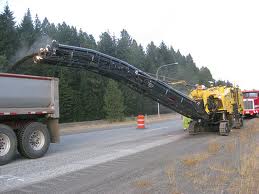 A road milling machine discharging asphalt into a tipper truck over its conveyor.