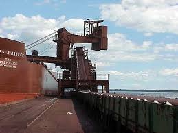 A dockside shiploader conveyor running the length of a quay beside a vessel.