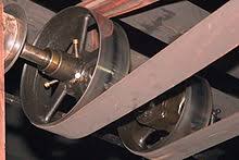 A flat belt running from a line shaft pulley down to the machine below it. A flat belt running from a line shaft pulley down to the machine below it.