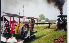 A traction engine driving a machine across a field by a flat belt. A traction engine driving a machine across a field by a flat belt.
