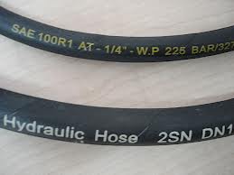 Two hydraulic hoses printed with their ratings, SAE 100R1 AT one quarter inch, working pressure 225 bar, and Hydraulic Hose 2SN. Two hydraulic hoses printed with their ratings, SAE 100R1 AT one quarter inch, working pressure 225 bar, and Hydraulic Hose 2SN.