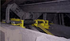 Idlers on yellow mounting frames supporting a loaded conveyor inside a plant. Idlers on yellow mounting frames supporting a loaded conveyor inside a plant.