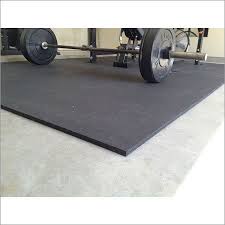 A thick rubber gym mat laid on a floor, with a loaded barbell resting on it. A thick rubber gym mat laid on a floor, with a loaded barbell resting on it.