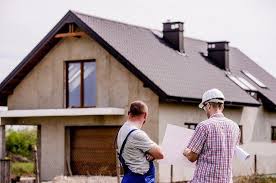 Two men on a building site holding insulation sheet against the wall of a house. Two men on a building site holding insulation sheet against the wall of a house.