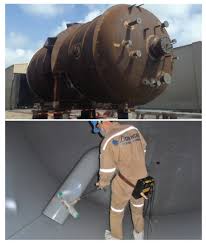 A steel process tank above, and below it an operator in protective clothing spraying its lining. A steel process tank above, and below it an operator in protective clothing spraying its lining.