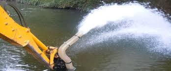 A yellow pump discharge arm throwing a jet of water out over a river. A yellow pump discharge arm throwing a jet of water out over a river.