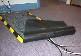 A dielectric carpet laid over cables on an office floor, its edge ramped and striped yellow and black.