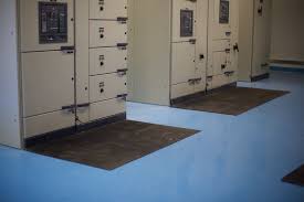 Blue safety matting on the floor of a substation, running between the panels.