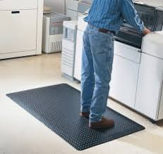 An operator working at a panel while standing on a rubber safety mat.