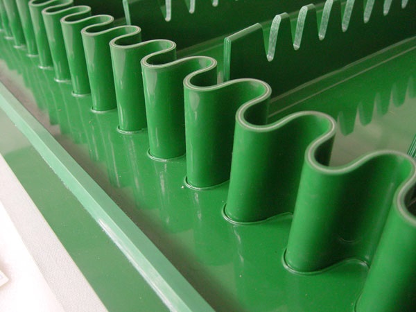 A green belt with corrugated sidewalls and cleats between them, for carrying loose material up an incline. A green belt with corrugated sidewalls and cleats between them, for carrying loose material up an incline.