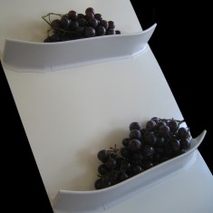 Two curved flights on a white belt, each holding a pile of dark berries. Two curved flights on a white belt, each holding a pile of dark berries.