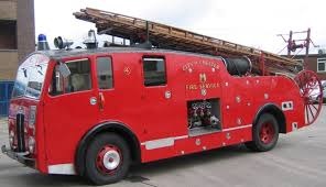 A fire appliance parked at a station, its ladder stowed along the roof.